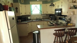 A compact kitchen with white cabinets, a built-in oven, a sink, and a small trash bin. - Quaint Village home in Allegany.1 mile from St. Bonaventure. (Allegany)