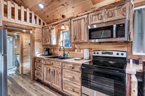 Une cuisine dotée de meubles en bois, d’un four à micro-ondes, d’une cuisinière et d’un évier.