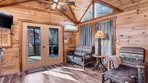 A wooden cabin interior with a ceiling fan, a sofa, a chair, and a lamp. - New Tiny Home w/Creek Near Gburg (Cosby)