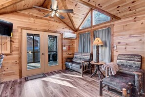 A wooden cabin interior with a ceiling fan, a sofa, a chair, and a lamp. - New Tiny Home w/Creek Near Gburg (Cosby)