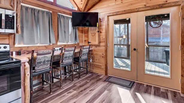 A wooden interior with a dining area, kitchen, and a TV mounted on the wall. - New Tiny Home w/Creek Near Gburg (Cosby)