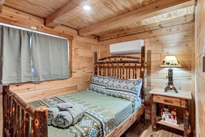 A wooden cabin interior with a bed, a lamp, and a small shelf with decorative items. - New Tiny Home w/Creek Near Gburg (Cosby)