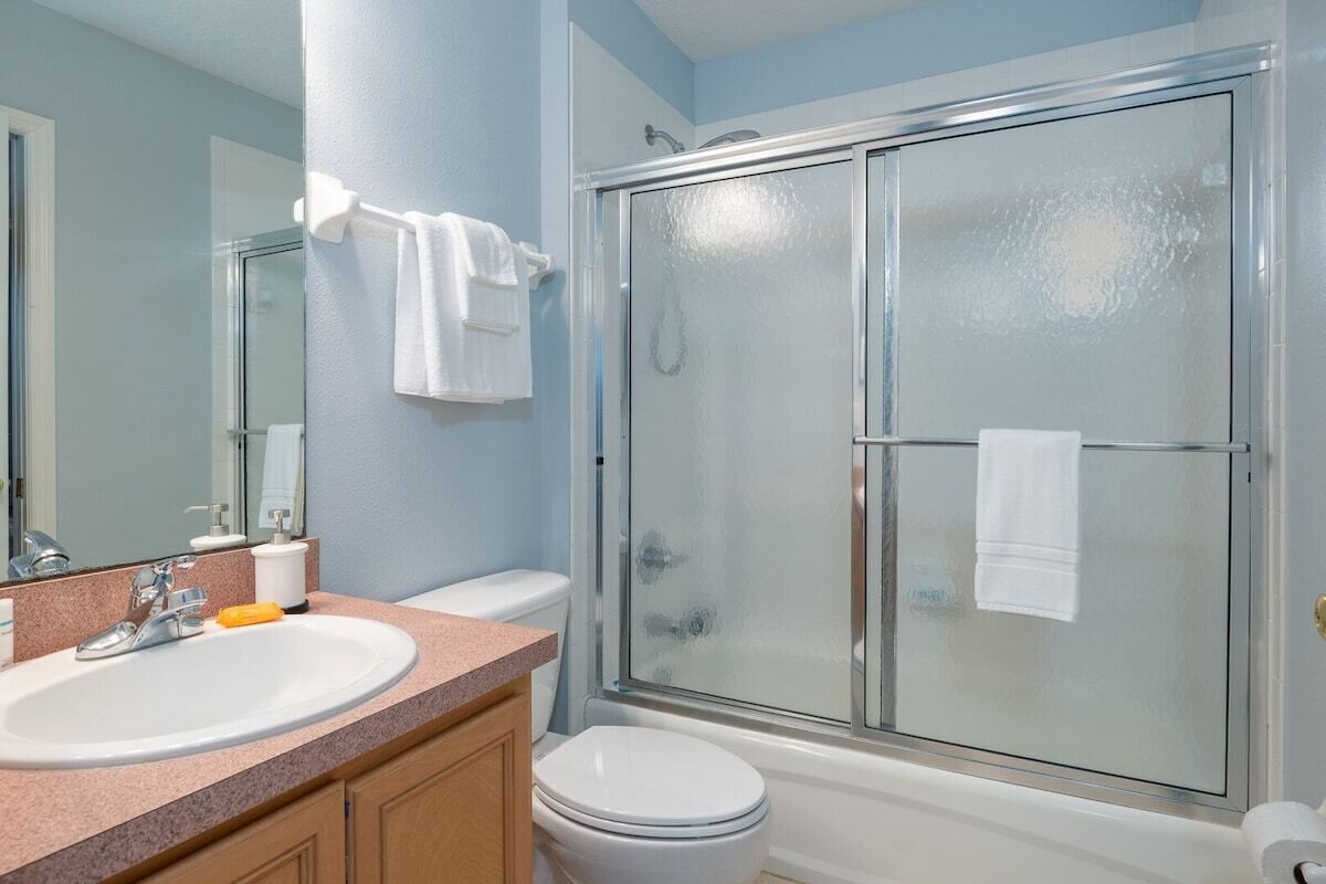 A bathroom with a sink, toilet, and glass-enclosed shower.