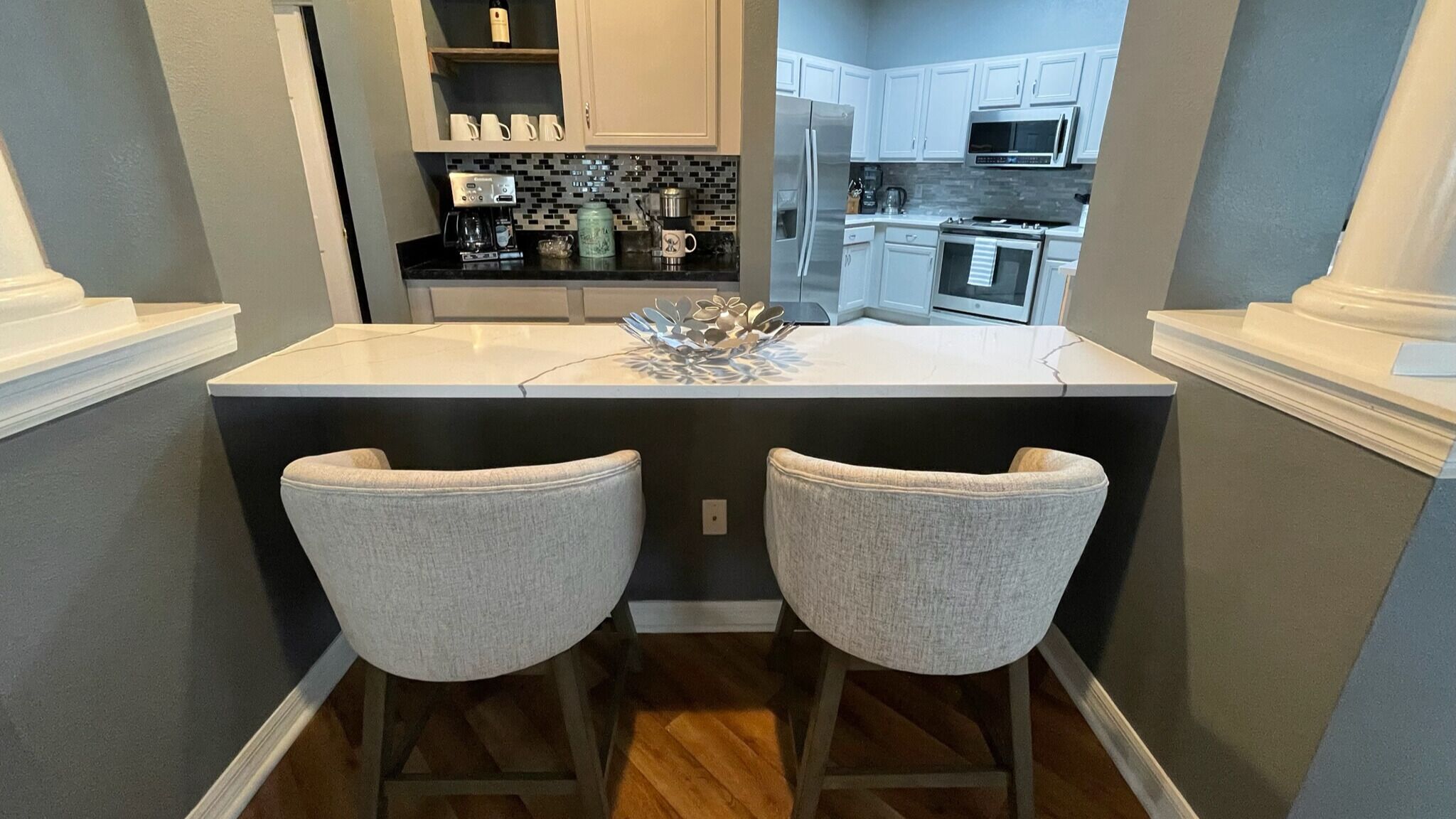 A kitchen with a central island, two bar stools, and modern appliances.