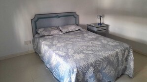 A bedroom with a bed, a nightstand, and a wall-mounted light. - Charming 2-bedroom apartment with AC, WiFi in Flic en Flac, 2 minutes from beach (Flic en Flac)