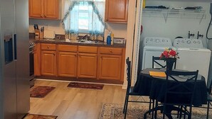 A modern kitchen with wooden cabinets, a refrigerator, and a dining area with a table and chairs.