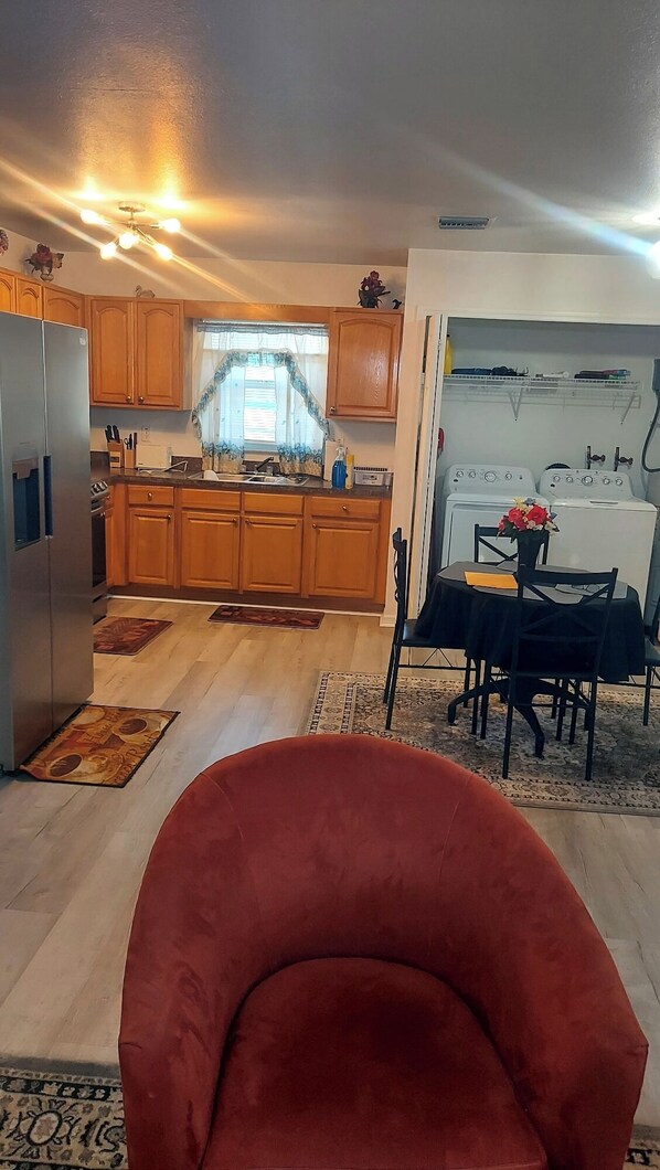 Una cocina moderna con armarios de madera, un refrigerador y un comedor con mesa y sillas.