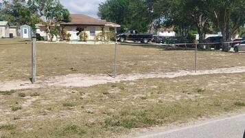 A residential area with houses, a grassy field, and a paved road.