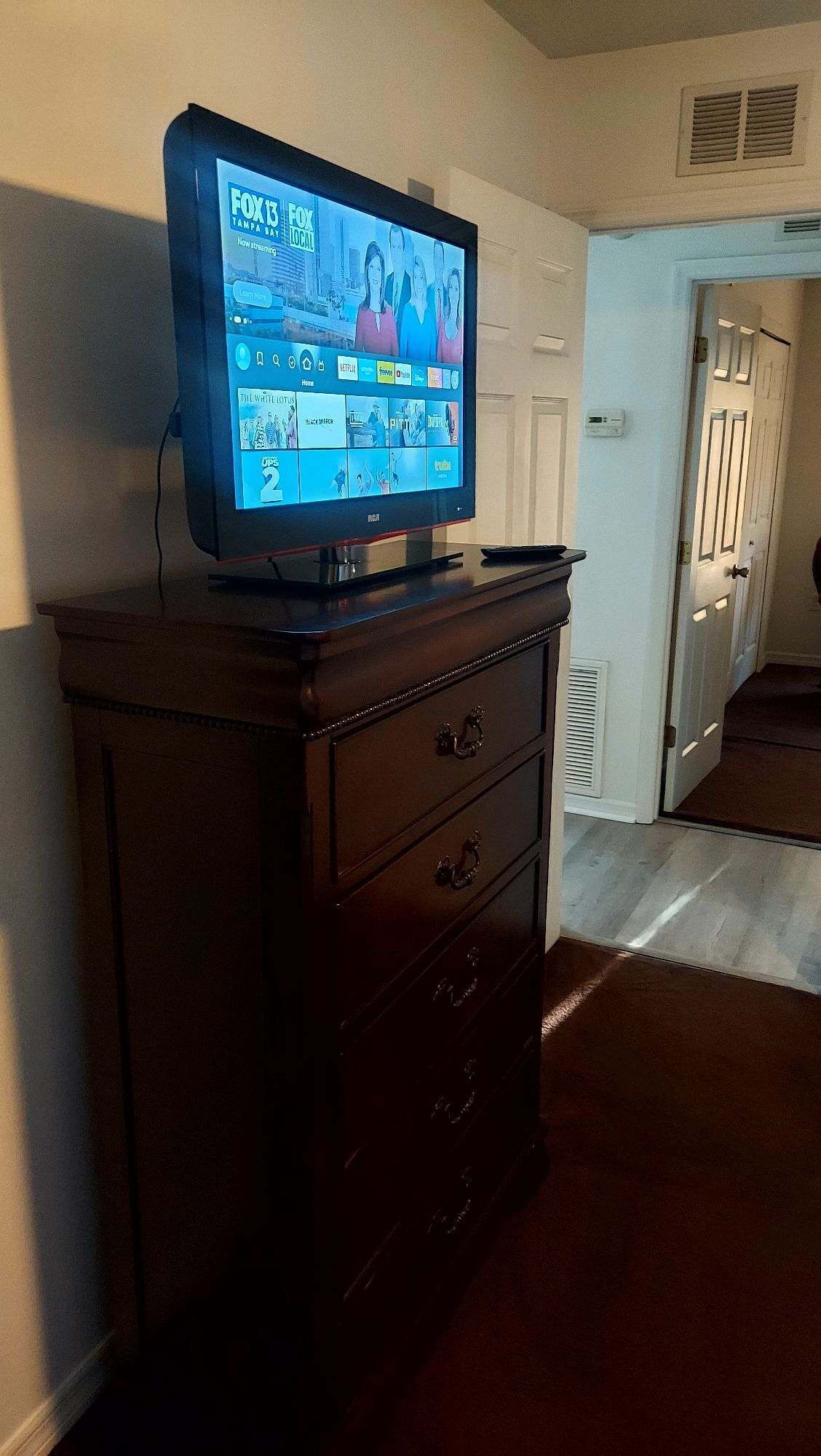 Un televisor de pantalla plana sobre un aparador de madera en un pasillo.