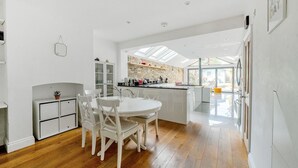 Una cocina moderna con una isla central, armarios blancos y un comedor con mesa y sillas redondas.