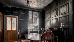 Un comedor con una mesa redonda, sillas de madera, una chimenea y una ventana con persianas.