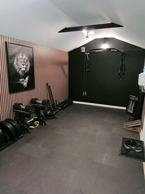 A home gym with a large mirror, weightlifting equipment, and a motivational poster.