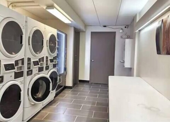 Une buanderie équipée de plusieurs machines à laver, avec une porte et un sol carrelé.