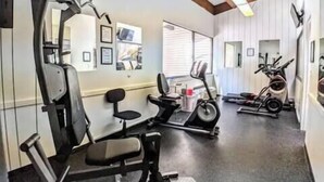 A gym with exercise equipment including a bench press, a treadmill, and a stationary bike.