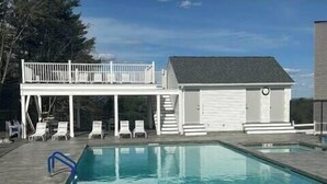 A swimming pool with lounge chairs and a small building with a garage.