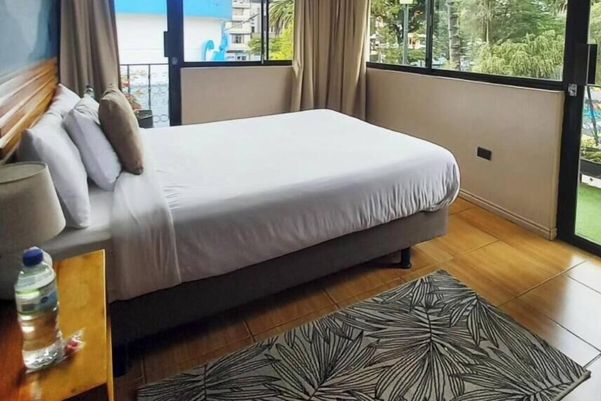 Une chambre à coucher avec un lit, des rideaux, une fenêtre et une vue sur un immeuble.