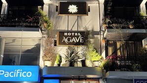 A hotel with a sign reading 'Hotel Agave,' a Pacifico sign, and a closed storefront with a 'Banco del Pacifico' sign.