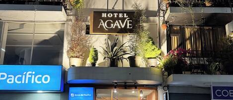 Un hotel con un cartel que dice 'Hotel Agave', un letrero de Pacifico y una tienda cerrada con un cartel de 'Banco del Pacifico'.