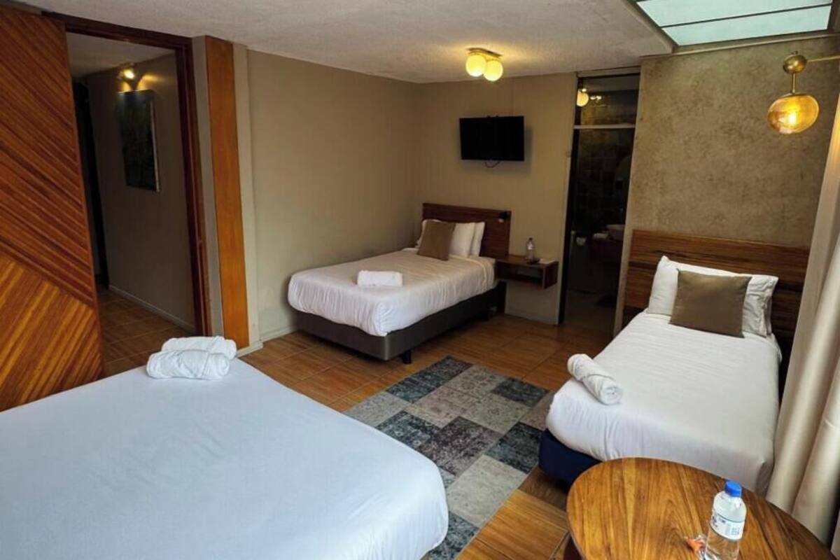 Une chambre d’hôtel avec deux lits, une petite table en bois, un téléviseur et une porte de salle de bain.