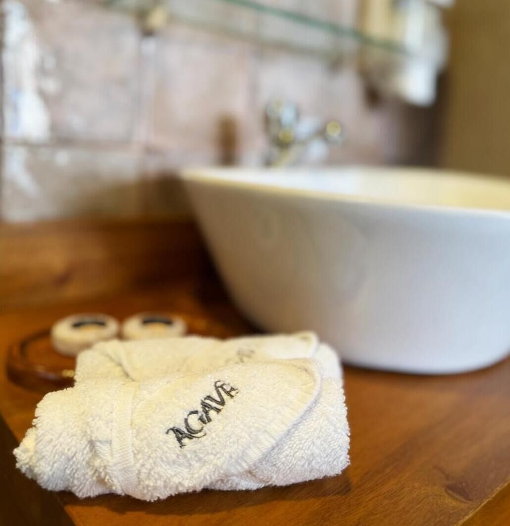 A bathroom with a white sink, a towel, and a pair of slippers on a wooden counter.