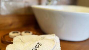 A bathroom with a white sink, a towel, and a pair of slippers on a wooden counter.