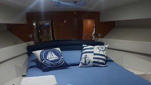 Un lit bien fait, recouvert d’une couvre-lit bleue, avec deux oreillers ornés de motifs marins et des serviettes pliées posées sur le côté.