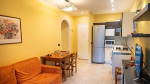 Un espacio habitable compacto con sofá, mesa de comedor y kitchenette.