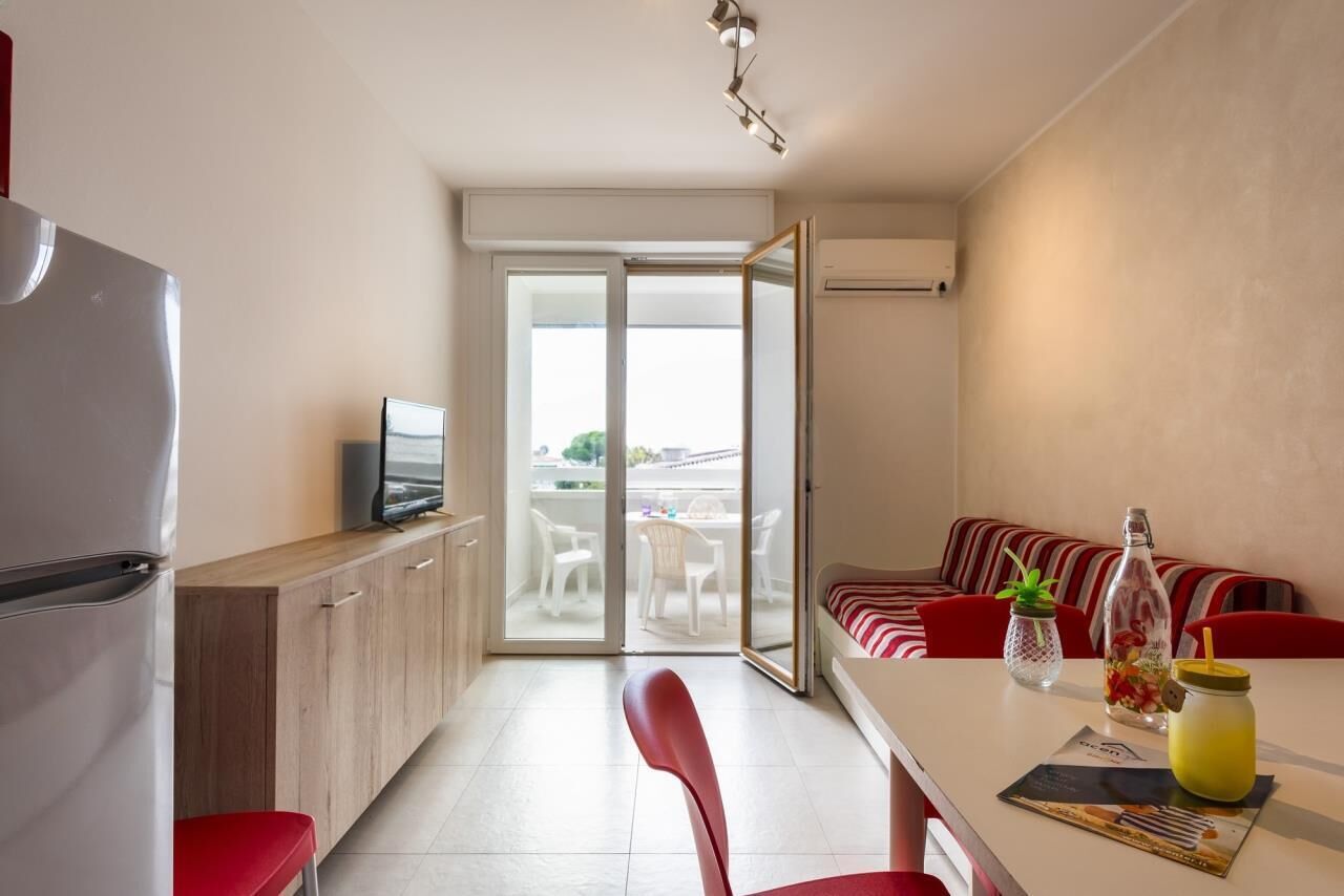 Una cocina moderna con refrigerador, televisor y comedor con mesa y sillas.