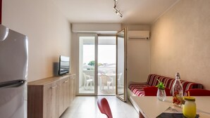 Una cocina moderna con refrigerador, televisor y comedor con mesa y sillas.