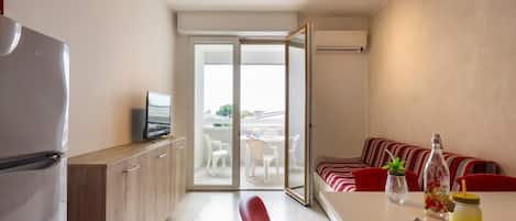 Eine moderne Küche mit Kühlschrank, Fernseher und Essbereich mit Tisch und Stühlen.