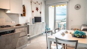 A modern kitchen with a built-in stove, a flat-screen TV, and a dining area with a table and chairs.