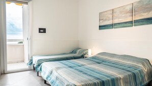 A room with two beds, a balcony door, and a wall-mounted artwork.
