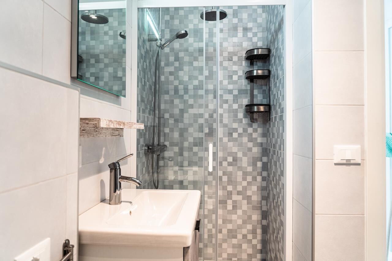 A modern bathroom with a glass-enclosed shower, a white sink, and a tiled backsplash.