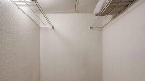 A small, empty room with white walls, a wooden floor, and a metal shelf against the wall. - Cozy 1BR in Prime Location (Oklahoma City)