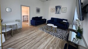 Ett modernt vardagsrum med en takfläkt, två soffor, ett soffbord och en matplats med ett bord och stolar.