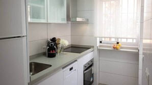 A modern kitchen with white cabinetry, a dishwasher, an oven, and a window with a view. - Comeback Looking for the Summer (Motril)