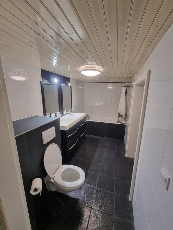 A modern bathroom with a toilet, sink, and bathtub.