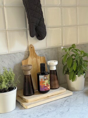 A kitchen counter with a cutting board, two spice bottles, a potted plant, and a black oven mitt hanging on the wall. - Dimora Patella - Florence
Spacious apartment 7 minutes from the city center (Firenze)