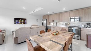 Una cocina moderna con comedor, que incluye una mesa de madera, sillas y un horno empotrado.