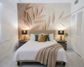 Een slaapkamer met een bed, twee bedlampen, een schilderij en een kledingkast.