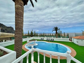 A pool surrounded by palm trees and cacti, with a view of the beach and mountains in the background. - GOLF SEA&POOL CACTUS VILLA (Buenavista del Norte)