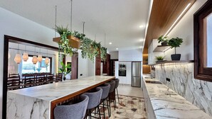 A modern kitchen with a marble countertop, bar seating, and hanging plants. - GOLF SEA&POOL CACTUS VILLA (Buenavista del Norte)