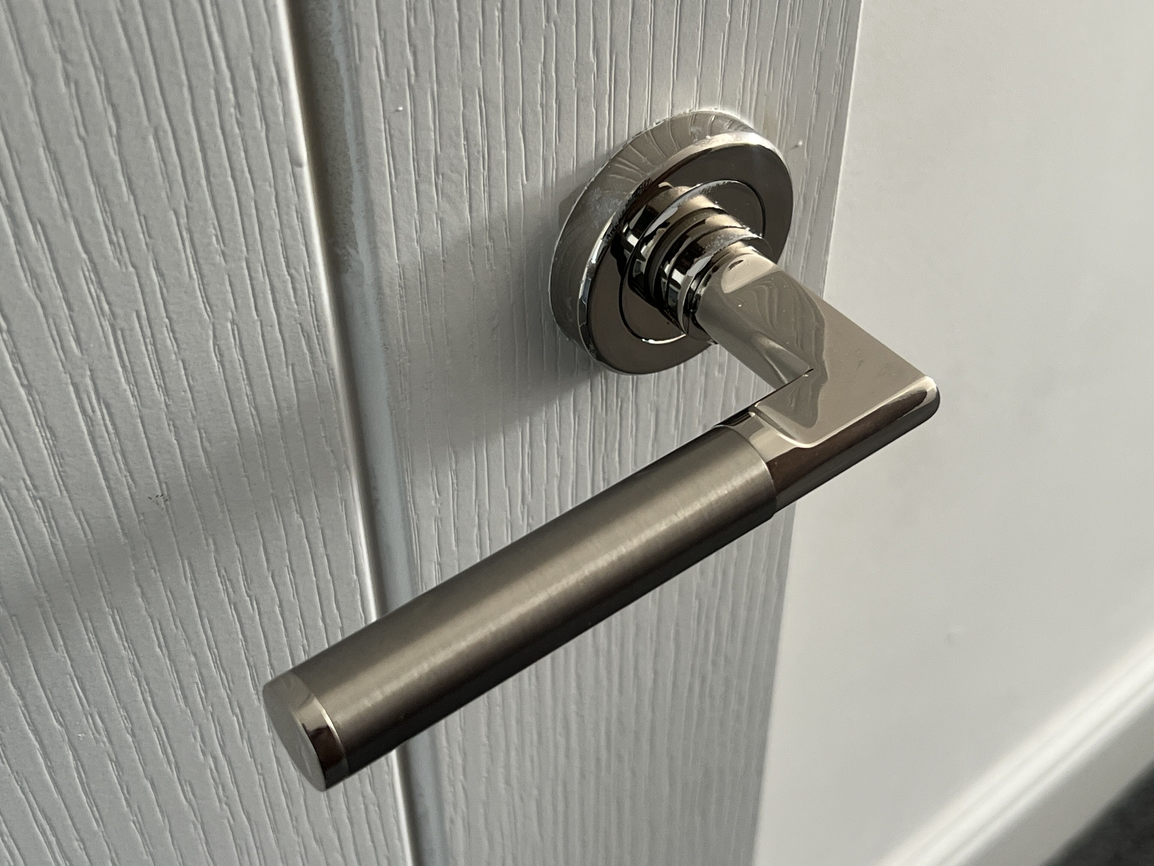 A metallic door handle on a textured door.