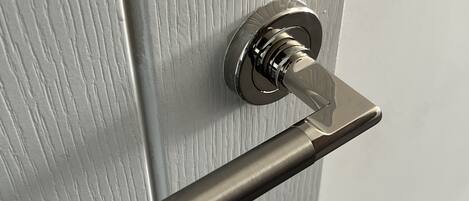 A metallic door handle on a textured door.