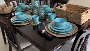 A dining table set with blue plates, cups, and a woven basket.