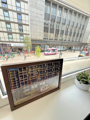 Vista desde una ventana que da a una tienda Marks & Spencer y un camión de comida rosa en el exterior.