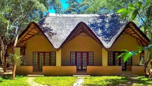 Een traditioneel huis met rieten dak, een centrale ingang en een pad naar de voordeur.