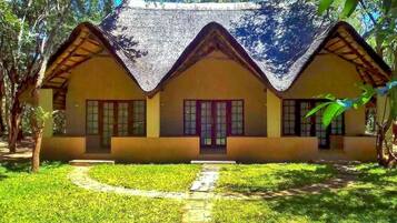 A traditional house with a thatched roof, a front porch, and a pathway leading to the entrance.