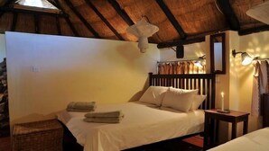 Een kamer met een bed, nachtkastje, lamp en plafondventilator.