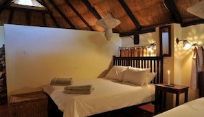 A room with a bed, a nightstand, a lamp, and a ceiling fan. - Bushfront Lodge (Livingstone)
